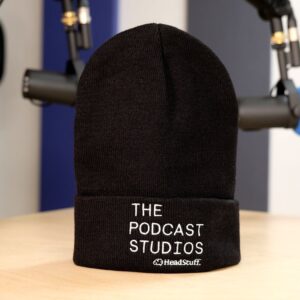 A black beanie hat emblazoned with the logo of The Podcast Studios Dublin